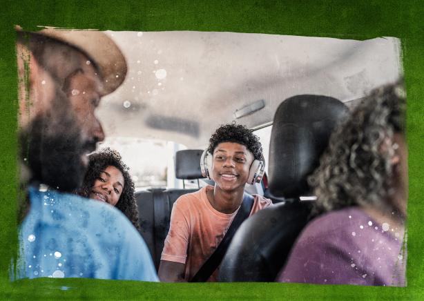 Two parents riding in a car talking to their two children in the back seat.