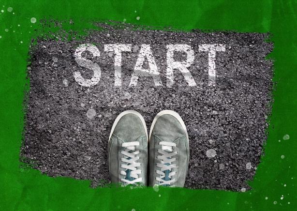 Feet standing on the asphalt with the word “start” written on it