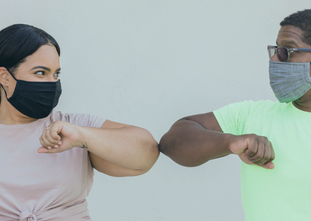 two people bumping elbows with masks on