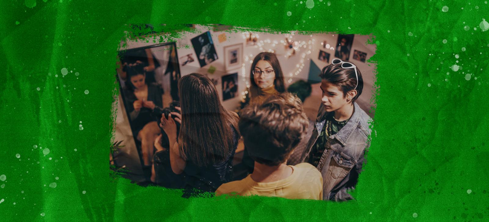 A group of teens talking in a bedroom. One of the girls in the group is getting ready in a mirro