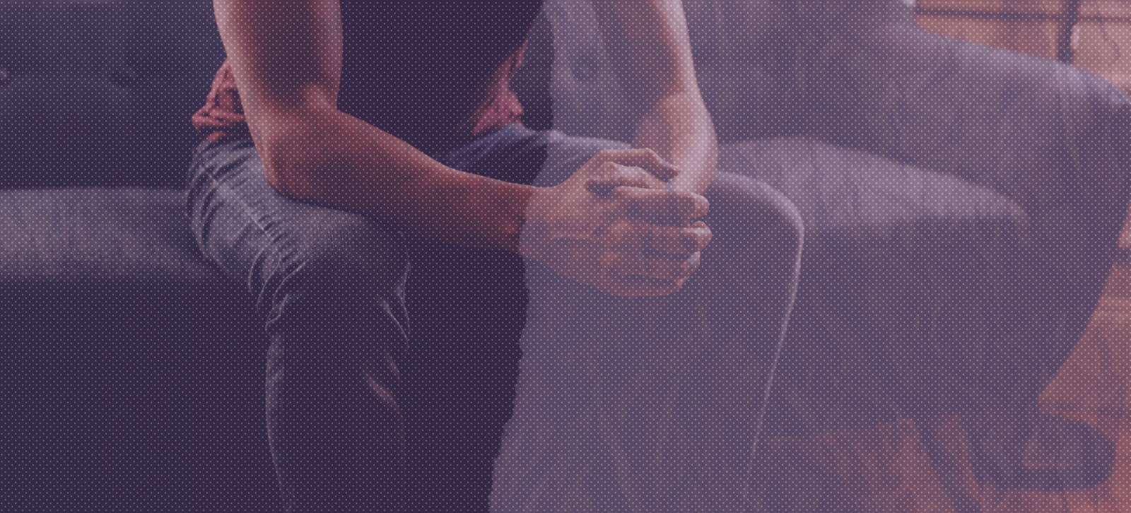  An image from the shoulders down of a person sitting on a gray couch.