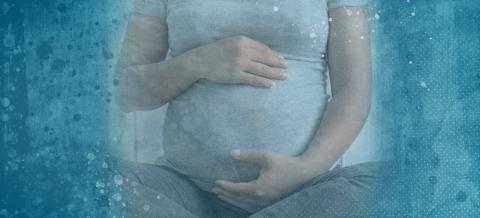 An image from the shoulders down of a mother holding her pregnant belly. She is wearing a light gray shirt and dark gray pants. There's a blue-speckled gradient filter over the image.