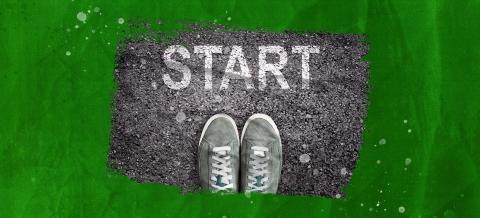 Feet standing on the asphalt with the word “start” written on it